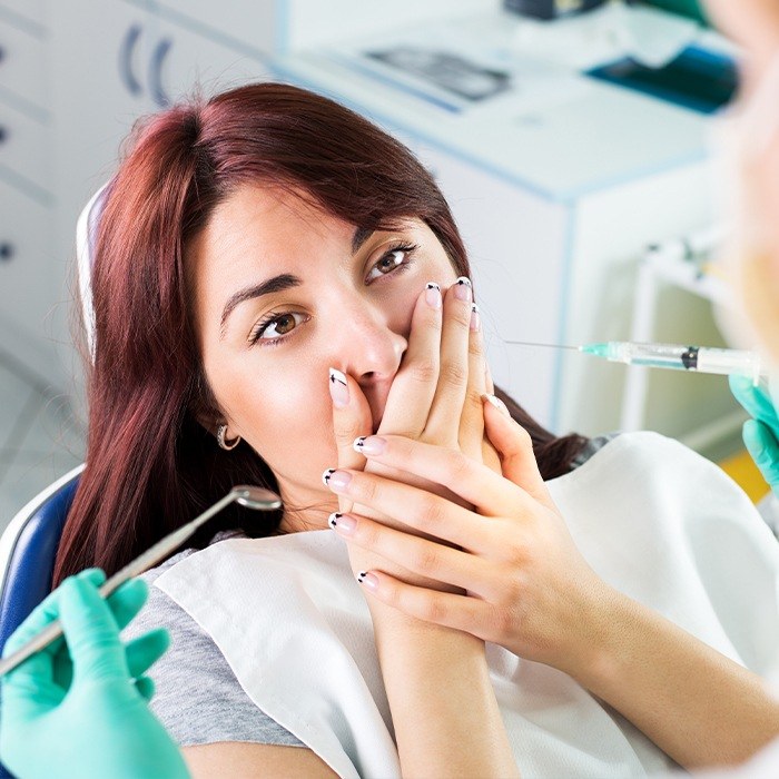 Woman in dental chair covering her mouth