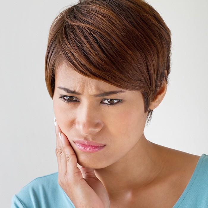 Woman in pain holding cheek