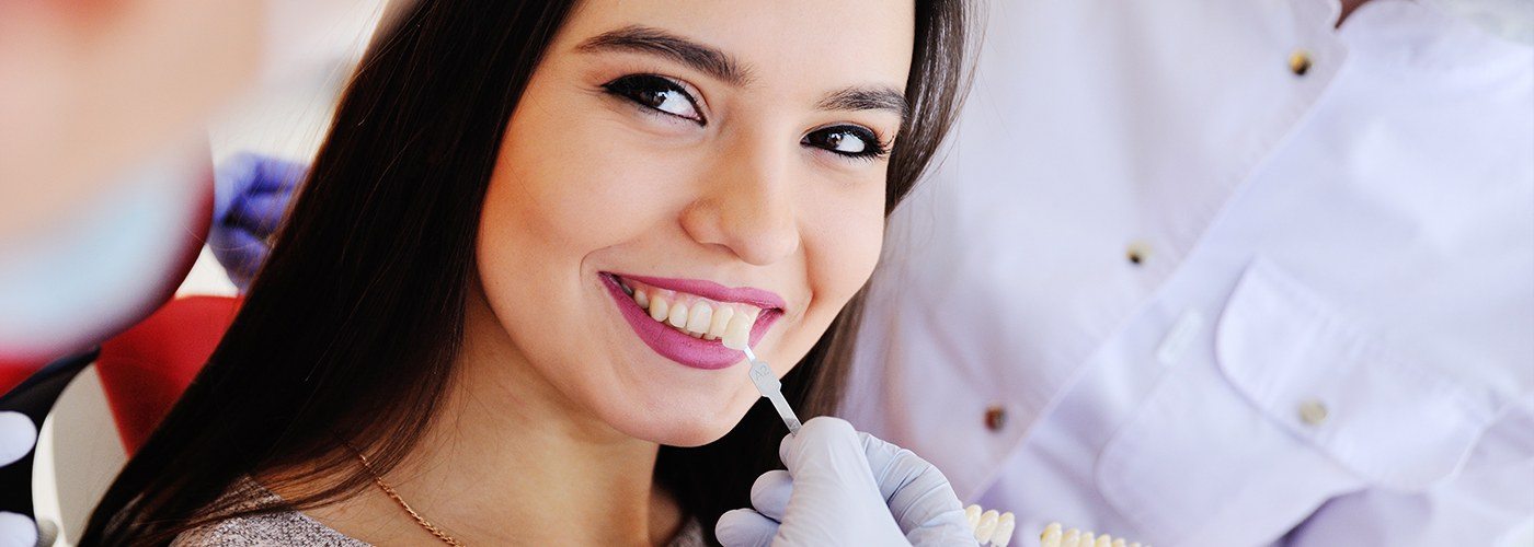 Woman's smile compared with tooth color chart