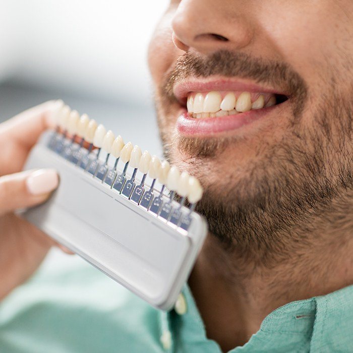 Closeup of smile compared with tooth color chart