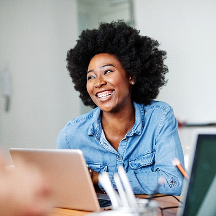 person laughing and sitting at an office desk with a laptop