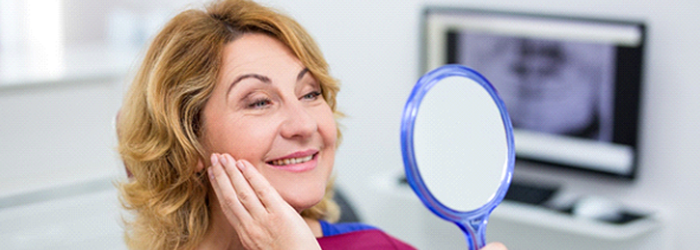 An older woman looking at her smile in the mirror