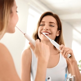 Woman brushing her teeth to prevent dental emergency in Lexington