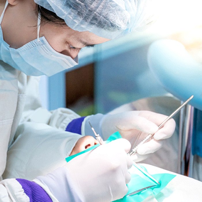 A dental professional performing complex dental work on a patient