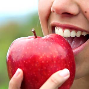 Closeup of patient with dental implants in Lexington eating an apple