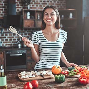 Woman with dental implants cooking healthy foods