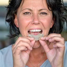 Woman wearing mouthguard to protect dental implants in Lexington