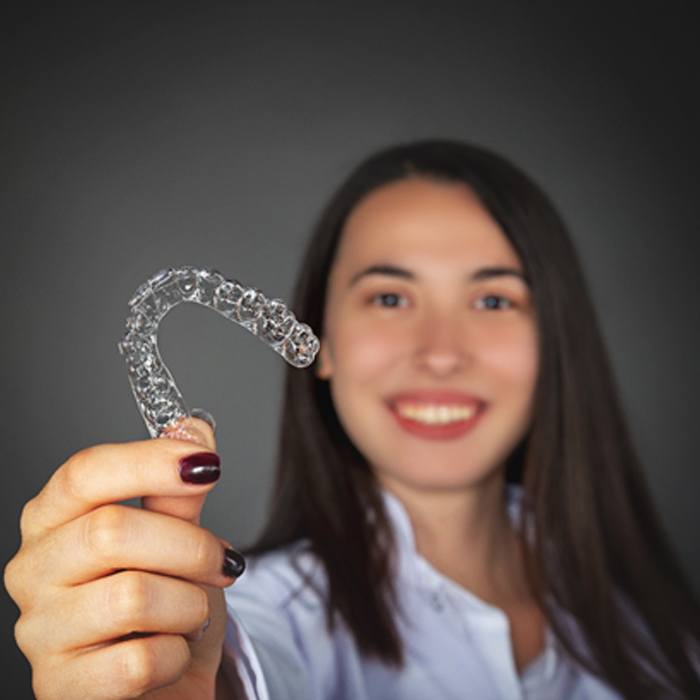 A young woman holding an Invisalign aligner