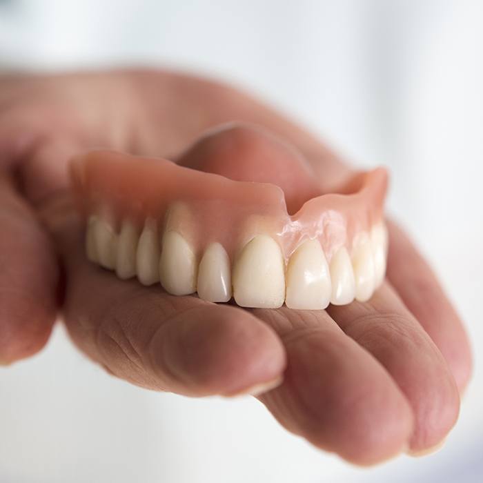 Hand holding a full denture