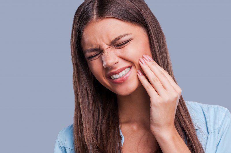 a young woman grabbing her cheek in pain