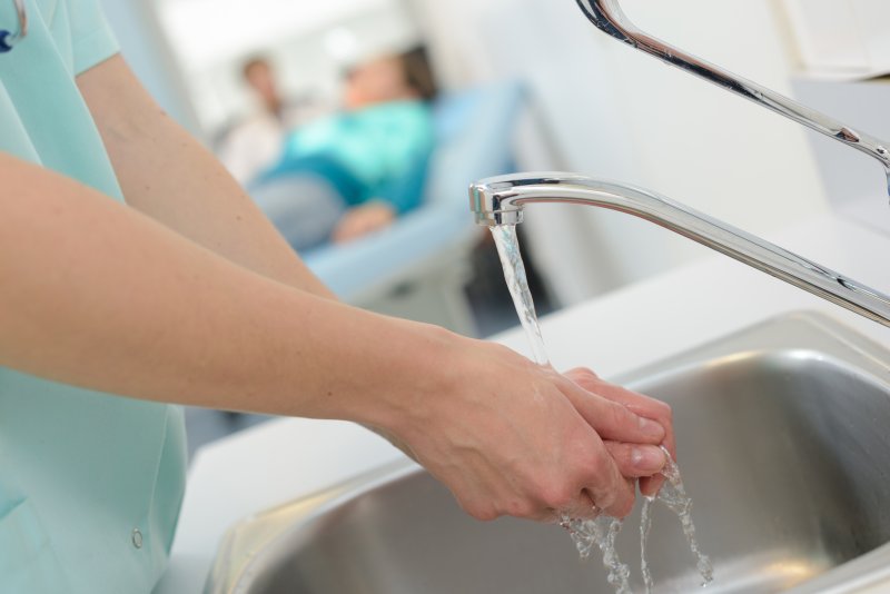 a dental staff member washing their hands prior to seeing a patient