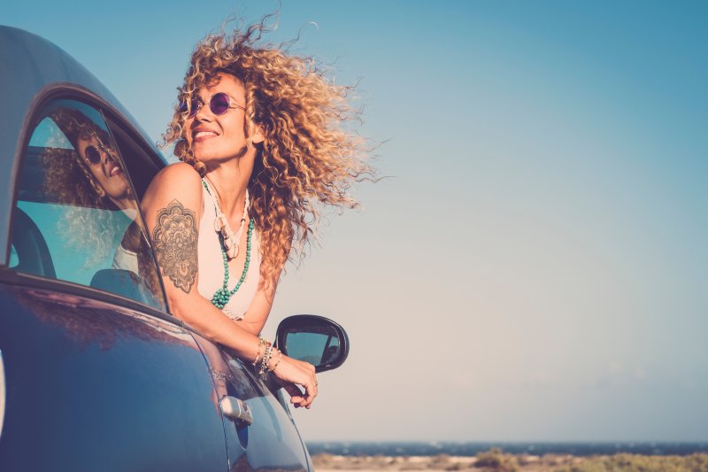 woman smiling out of a car during summer 