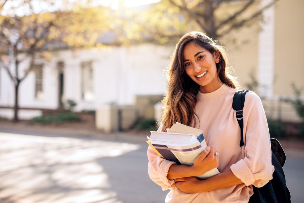 College student smiling while holding books