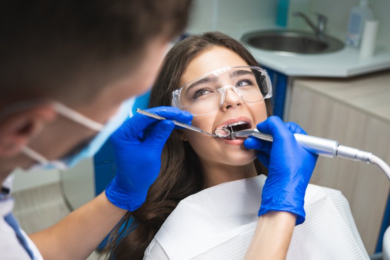 A dentist performing a root canal retreatment on a woman